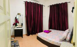 a bedroom with red curtains and a bed and a mirror at Nurul Amin Guest House Pantai Cahaya Bulan Kota Bharu in Kota Bharu