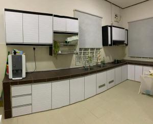 a kitchen with white cabinets and a counter top at Nurul Amin Guest House Pantai Cahaya Bulan Kota Bharu in Kota Bharu