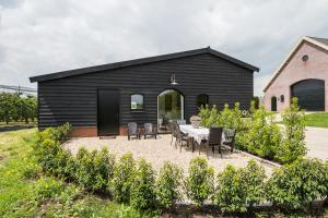 a black house with a table and chairs in a garden at De Oosterling in Deil