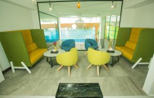 a waiting room with yellow and blue chairs and tables at Hotel Omni Residency Dhaka in Dhaka