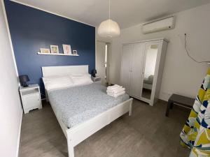 a bedroom with a white bed and a blue wall at La Casa del Riccio in Tindari