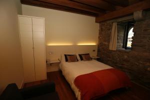 a bedroom with a bed and a stone wall at Larramendi Torrea in Azcoitia
