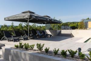 eine Terrasse mit Stühlen und einem Sonnenschirm darüber in der Unterkunft Plitvice Holiday Resort in Grabovac