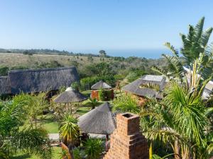 uma vista para um resort com telhados de palha e para o oceano em The Owls Inn Country Villa's em George