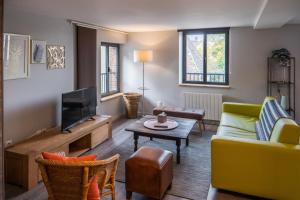 a living room with a couch and a tv at LOGIS Hotel-Restaurant Le Relais d'Aligre in Châteauneuf-en-Thymerais