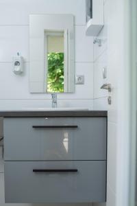 a white bathroom with a sink and a mirror at Twins Apartman Hévíz in Hévíz