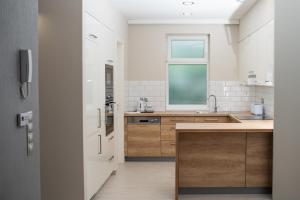 uma cozinha com paredes brancas e armários de madeira e uma janela em Twins Apartman Hévíz em Hévíz