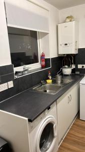 a kitchen with a washing machine and a sink at Smalinz Homes Finchley in London
