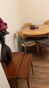 a wooden table with a vase of flowers and a table and chairs at Smalinz Homes Finchley in London