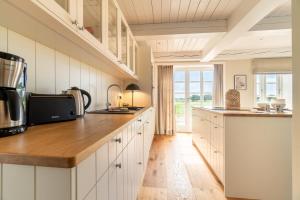 a kitchen with white cabinets and a wooden counter top at Sommer Hüs in Klein Dunsum