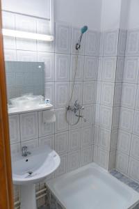 a white bathroom with a sink and a shower at Hotel Turist in Pucioasa