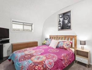 a bedroom with a large bed and a tv at Chill at our Igloo cottage - 100m stroll to beach in Portarlington