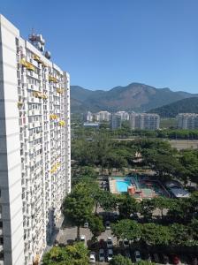 un edificio de apartamentos con piscina y montañas al fondo en Condominio Barra Sul - Edifício Marapendí, en Río de Janeiro