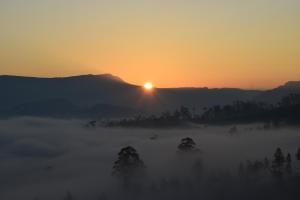 un lever de soleil brumeux avec le soleil se lever au-dessus des montagnes dans l'établissement Citadel Lindula, à Lindula