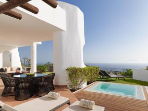 a patio with a pool and a table and chairs at Las Terrazas de Abama Suites in Guía de Isora