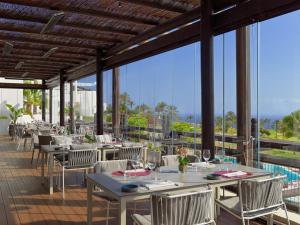 a dining room with tables and chairs and windows at Las Terrazas de Abama Suites in Guía de Isora