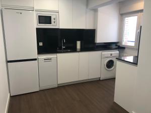 eine Küche mit weißen Schränken, einer Waschmaschine und einem Trockner in der Unterkunft Apartamento Santander in Santander