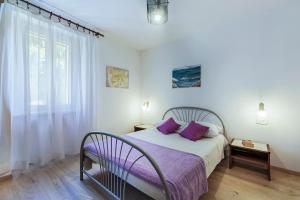 a bedroom with a bed with purple pillows and a window at House Katuri 1059 in Labin