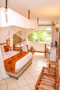 een slaapkamer met een groot bed met een baldakijn bij Kahama Hotel Mombasa in Bamburi