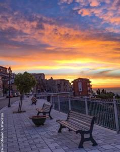 two benches on a sidewalk with a sunset in the background at B&B Belvedere Castelluccio Valmaggiore in Castelluccio Valmaggiore