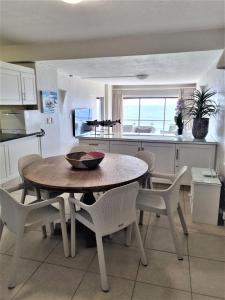 405 Bermudas - by Stay in Umhlanga في ديربان: مطبخ مع طاولة وكراسي في غرفة