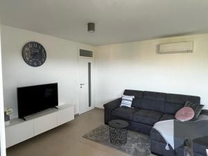 a living room with a couch and a clock on the wall at Apartman Ana in Sveti Anton