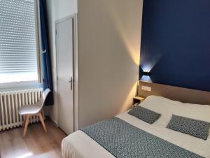 a bedroom with a bed and a blue wall at Hotel Des Lices - Angers in Angers
