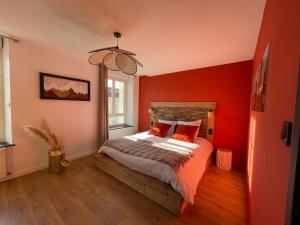 een slaapkamer met rode muren en een bed met rode kussens bij Les 2 Biches, hyper centre et spacieux Gérardmer in Gérardmer