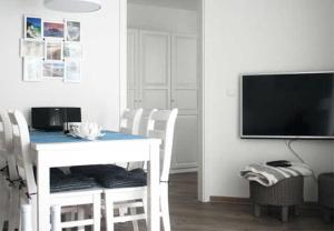 ein Esszimmer mit einem weißen Tisch und einem TV in der Unterkunft Haus Meeresblick - Ferienwohnung Am Strand (Ref. 128682u2) in Baabe