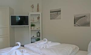 ein weißes Wohnzimmer mit einem TV und weißen Handtüchern in der Unterkunft Haus Meeresblick - Ferienwohnung Am Strand (Ref. 128682u2) in Baabe + 9 Fotos