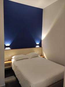 1 dormitorio con cama blanca y pared azul en Hotel Des Lices - Angers, en Angers