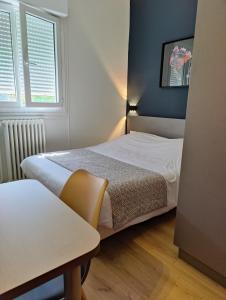 1 dormitorio pequeño con 2 camas y mesa en Hotel Des Lices - Angers, en Angers