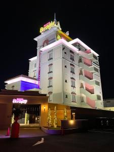 a large white building with a neon sign on it at ホテルバースデー岐阜西店 HOTEL Birthday GifuWest in Gifu