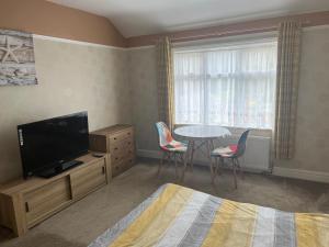 a bedroom with a tv and a table and chairs at Hereward in Wisbech