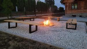 a fire pit with two picnic tables and afire at Sołtysówka in Wielogłowy