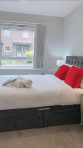 ein großes Bett mit roten Kissen und einem Fenster in der Unterkunft Mnitri apartment in Luton