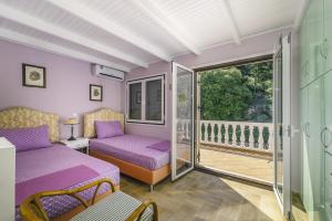 um quarto com camas roxas e uma varanda em VILLA PANOREA em Ayios Nikitas