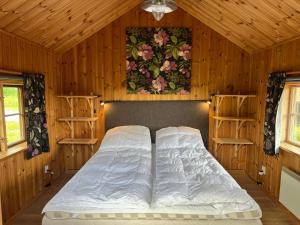 Villa Klockarbo - Stugor - Cabins في تالبيرغ: غرفة نوم بسرير في غرفة خشبية