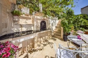 un patio con mesas, sillas, flores y escaleras en Apartment OM en Povlja