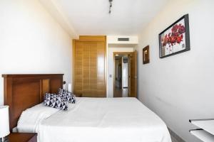 Schlafzimmer mit einem weißen Bett mit einem Kopfteil aus Holz in der Unterkunft Apartamento frente al mar in Benicarló