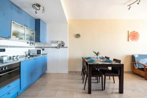 a kitchen with blue cabinets and a table with chairs at Apartamento frente al mar in Benicarló +7 photos