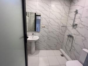 a white bathroom with a sink and a shower at Batumi Hotel R&M in Batumi