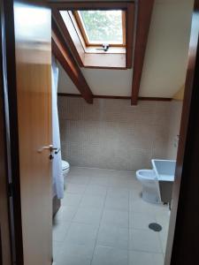 a bathroom with a window and a toilet and a sink at Hotel La Plaza in Proaza