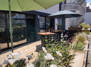 una terraza de madera con sombrilla y algunas flores en Villa Raphaëlle #3 Centre ville avec parking, en Le Havre
