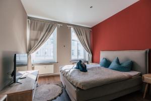- une chambre avec des murs rouges et un lit avec des oreillers bleus dans l'établissement Luga Homes - Mitte, à Leipzig