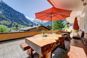 Haus Tuklar في براند: طاولة خشبية مع مظلة حمراء على شرفة