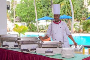 a chef standing in front of a table with plates at Kahama Hotel Mombasa in Bamburi