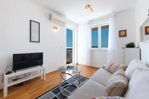 a white living room with a couch and a tv at Fortuna apartment in Dubrovnik