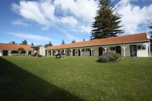 a building with a green lawn in front of it at Waikanae Beach TOP 10 Holiday Park in Gisborne