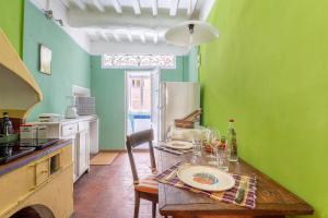 a kitchen with a wooden table and green walls at Anfiteatro Lucca in Lucca
